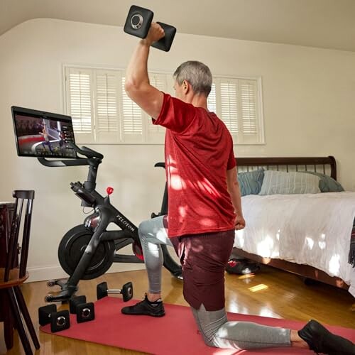 Man working out with dumbbell on a stationary bike in home gym.