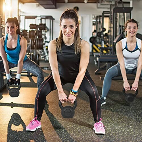 Three women exercising with kettlebells in a gym.